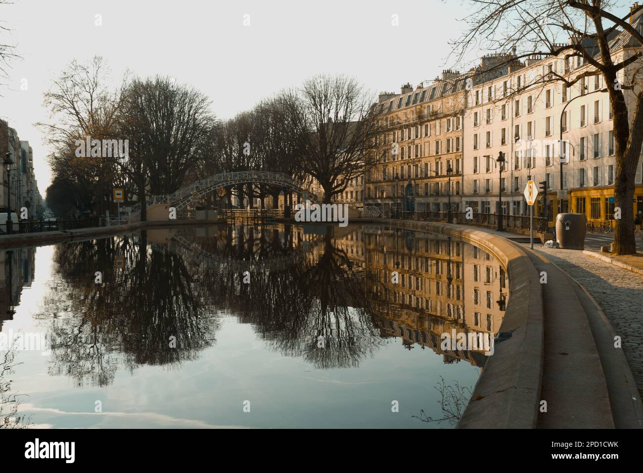 Die Gebäude Spiegeln Sich Im Stillen Wasser Des Canal Saint Martin, Paris Frankreich Am Frühen Morgen Im Frühling Wider Stockfoto