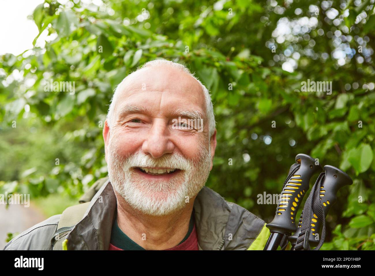 Porträt eines lächelnden älteren Mannes mit Wanderstöcken in der Jacke im Urlaub Stockfoto