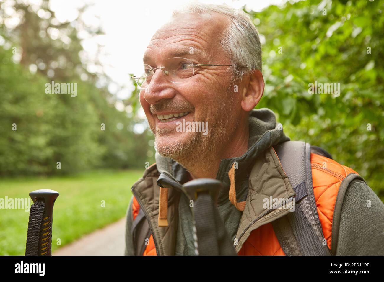 Lächelnder älterer Mann mit Brille in Jacke, der während des Urlaubs wegschaut Stockfoto