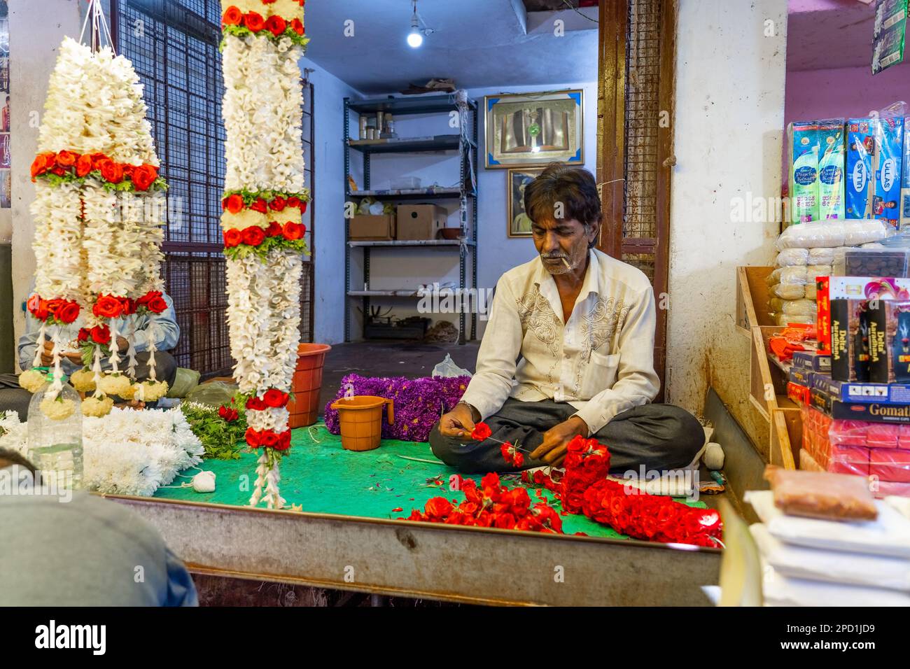 Mysore, Indien - 12.01.2023. Blumenverkäufer, der auf dem Markt in Mysore Blumendekorationen und Girlanden herstellt. Hochwertiges Foto Stockfoto