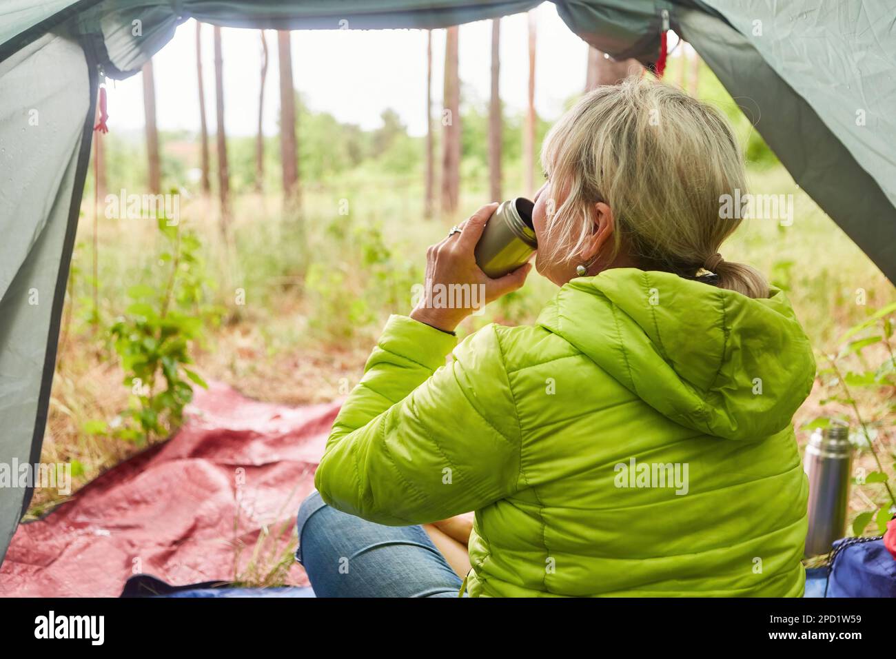 Seniorin trinkt Tee während der Ferien im Zelt auf dem Campingplatz Stockfoto