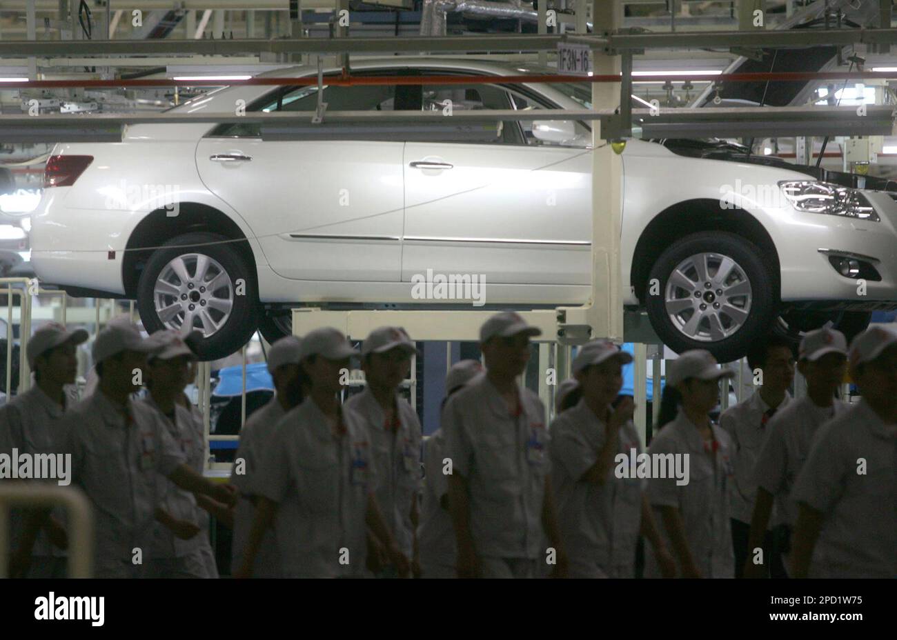 Workers walk past a Toyota Camry on an assembly line at the Toyota plant in Guangzhou, in south China's Guangdong province, Tuesday, May 23, 2006. Toyota Motor Corp. on Tuesday rolled out its first made-in-China Camry from a new factory that the Japanese automaker hopes will help it to catch up with rivals in the world's fastest-growing car market. (AP Photo) ** CHINA OUT ** Stockfoto