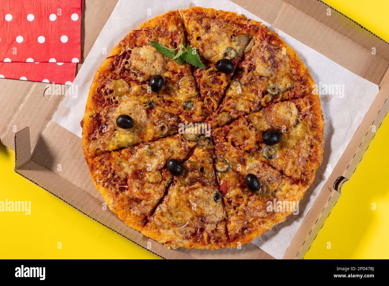 Pizza mit Gemüse und Wurst in einer Pappschachtel für die Heimlieferung auf gelbem Hintergrund, Draufsicht Stockfoto