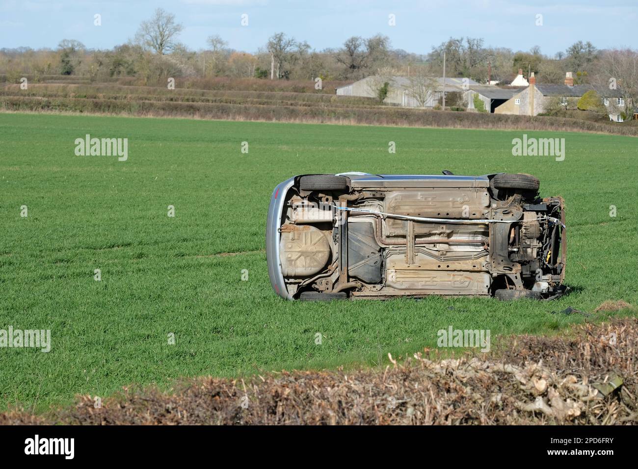 Das Auto ist auf einem ländlichen Feld umgefallen, nachdem es im März 2023 in Gloucestershire UK durch eine Hecke am Straßenrand gestürzt ist Stockfoto