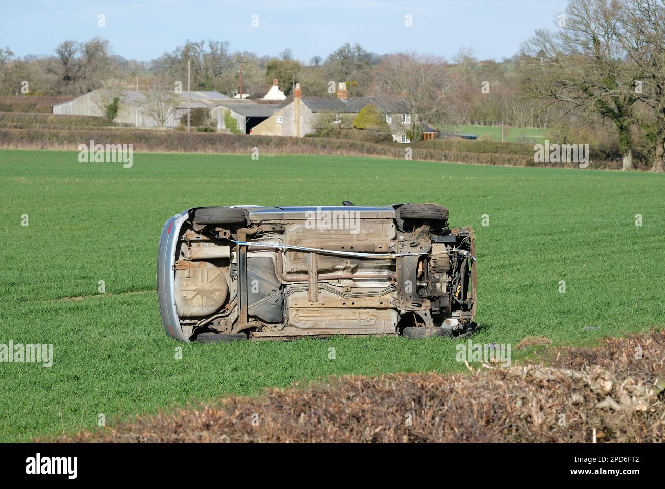 Das Auto ist auf einem ländlichen Feld umgefallen, nachdem es im März 2023 in Gloucestershire UK durch eine Hecke am Straßenrand gestürzt ist Stockfoto