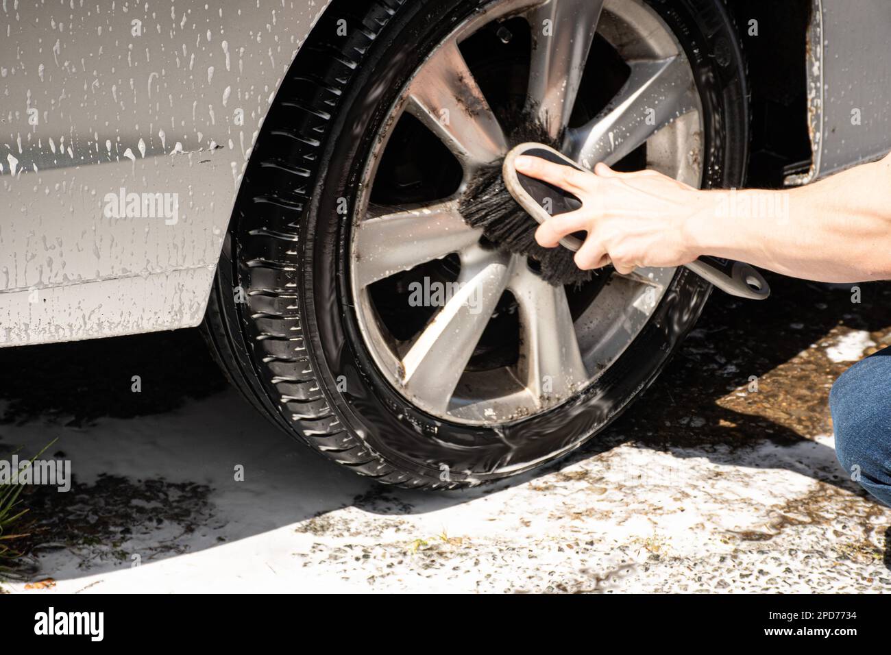 Zwei Masern reinigen einen silbernen Auto-Sprühschaum mit einem Hochdruckreiniger ein Auto waschen Stockfoto