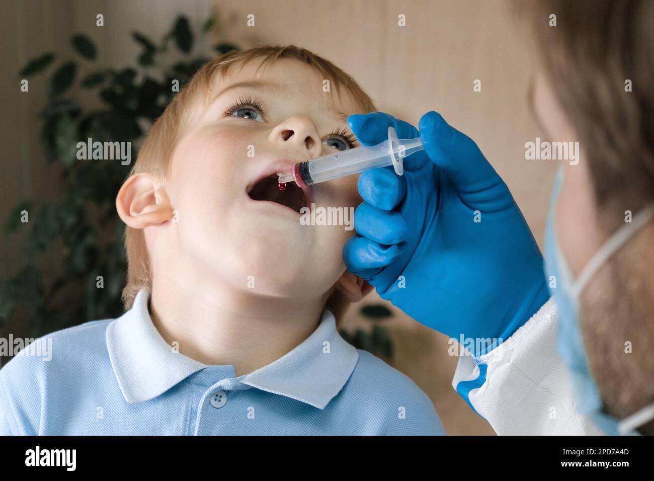 Der Junge bekommt Polio-Tropfen. Arztmachen zum Kind orale Schutzimpfung gegen Infektionen. Kleiner blonder Haarjunge im Krankenhaus. Kindergesundheitsfürsorge und Kinderkrankheiten Stockfoto