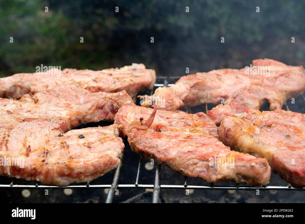 Fleischschaschlik, auch bekannt als Shish Kebab, wird auf einem Holzkohlegrill gegrillt. Fleischscheiben auf Stahlspießen aus der Nahaufnahme. Köstliches traditionelles kaukasisches Fleischgericht. Hochwertiges Foto Stockfoto