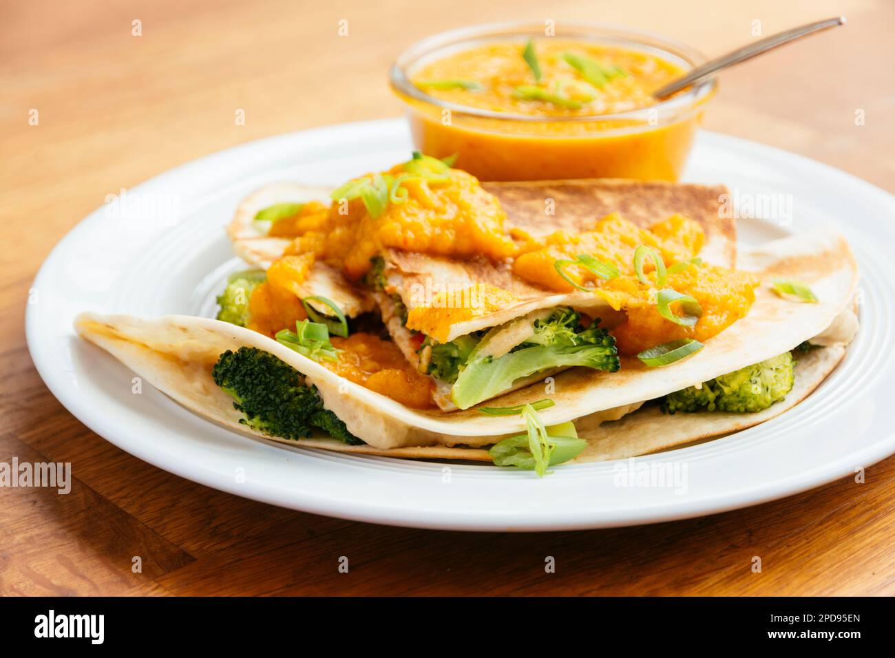 Teller mit veganen Brokkoli Quesadillas, serviert mit einer Aprikosen-Karotten-Sauce. Stockfoto