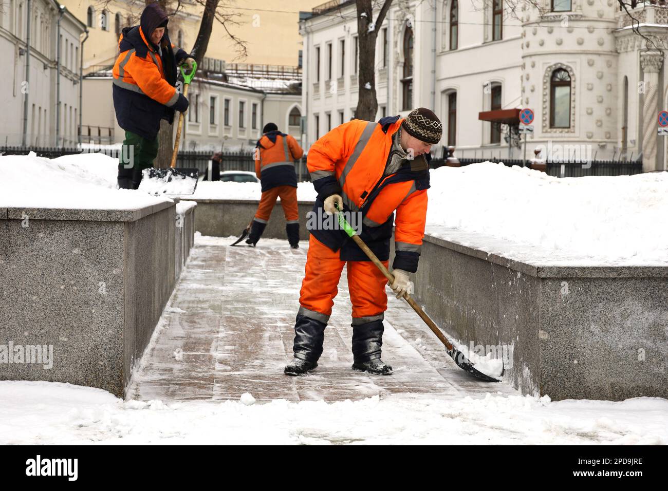Männer, Arbeiter, die Schnee mit Schaufeln säubern, Schneeräumen in der Stadt. Frühlingswetter, Straßenreinigung in Moskau Stockfoto