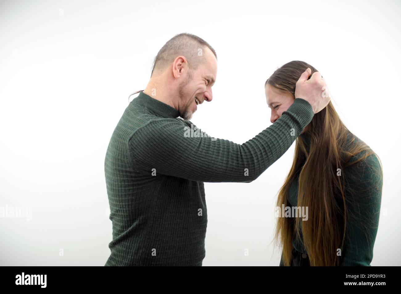Ein Mann nimmt sich Mädchen für Haar von beiden Seiten und schlägt sich Kopf und Knie an, zeigt Empfang Sportschule lustige Situationen schlechte Einstellung gegenüber einer Frau, lehrt Ehepaar auf weißem Hintergrund zu bekämpfen Stockfoto