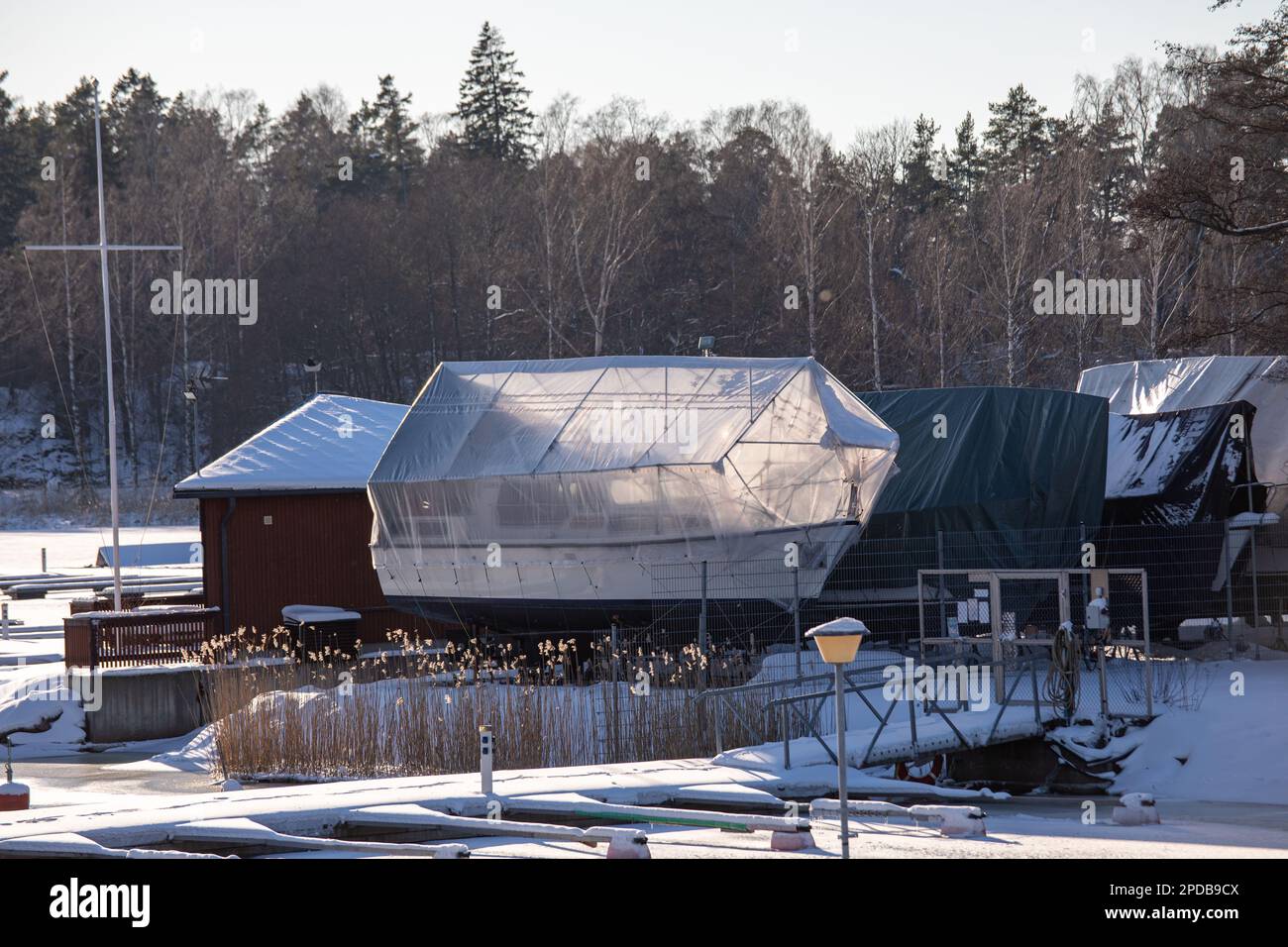 Mit Kunststoffplanen überzogene Boote auf Winterlager am Munkan venekerho im Munkkiniemi-Bezirk Helsinki, Finnland Stockfoto
