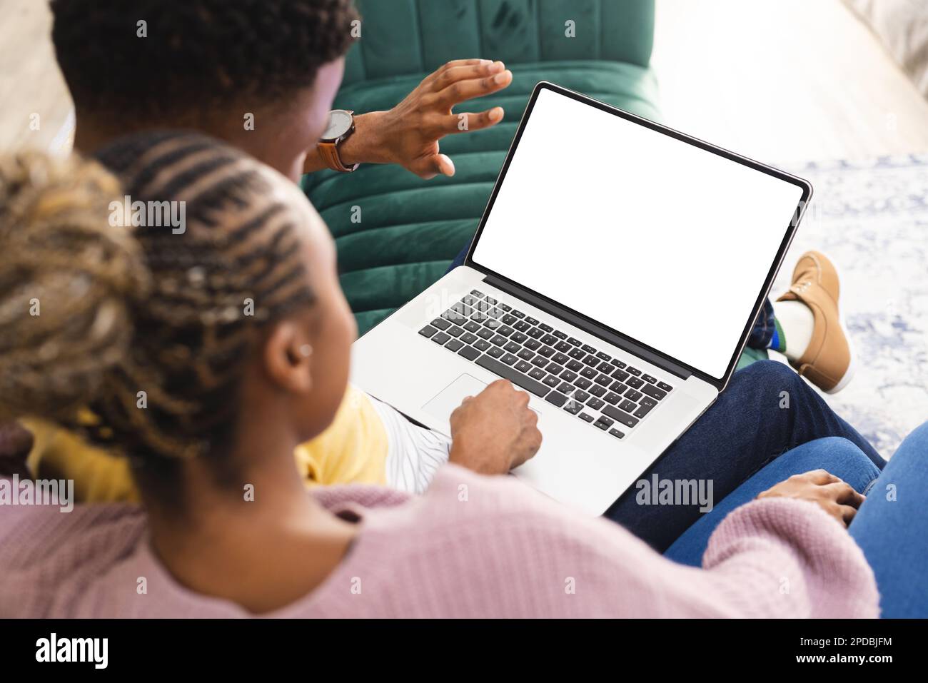 Glückliches afroamerikanisches Paar, das auf dem Sofa sitzt und einen Laptop mit Kopierbereich im Wohnzimmer benutzt. Verbringen Sie Zeit, Lebensstil und häusliches Leben. Stockfoto