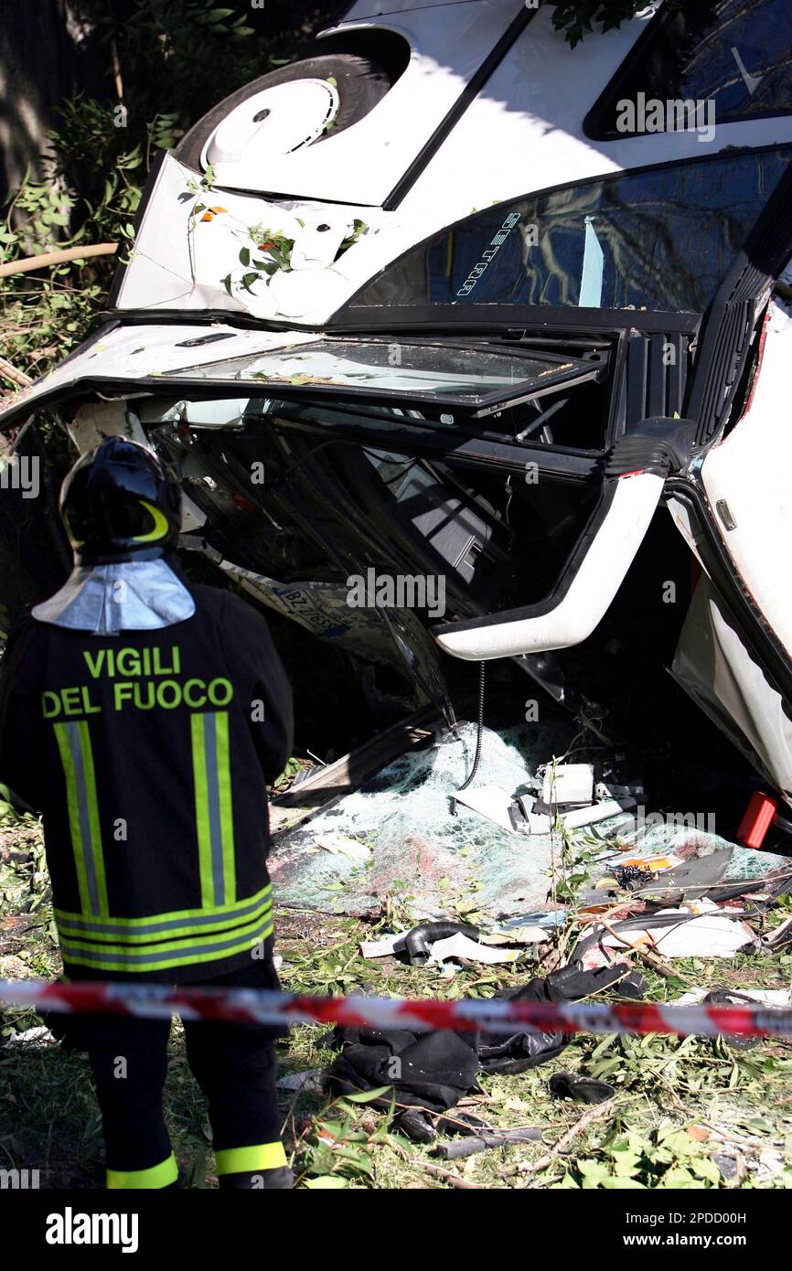 An Italian firefighter looks at the wreckage of a bus in yard of a ...