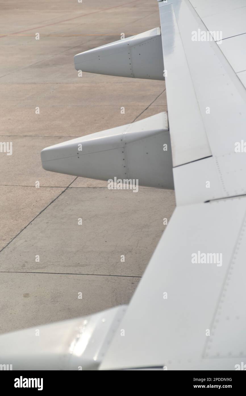 Detail eines Flügels eines geparkten gewerblichen Passagierflugzeugs, Blick aus einem Fenster. Minimalistisches Bild für das Reisekonzept. Stockfoto