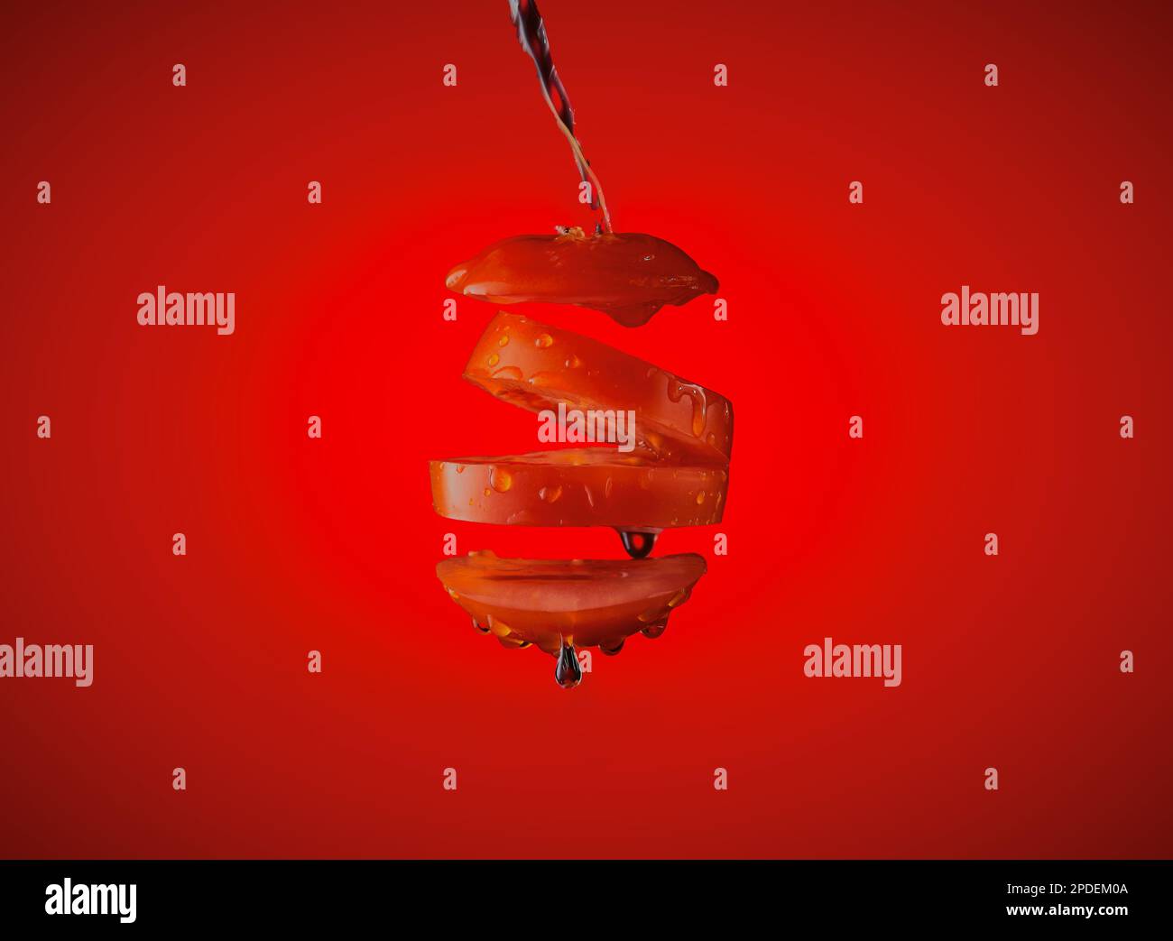 In der Luft suspendierte Tomaten auf einem roten Hintergrund mit Wasserspritzern. Stockfoto