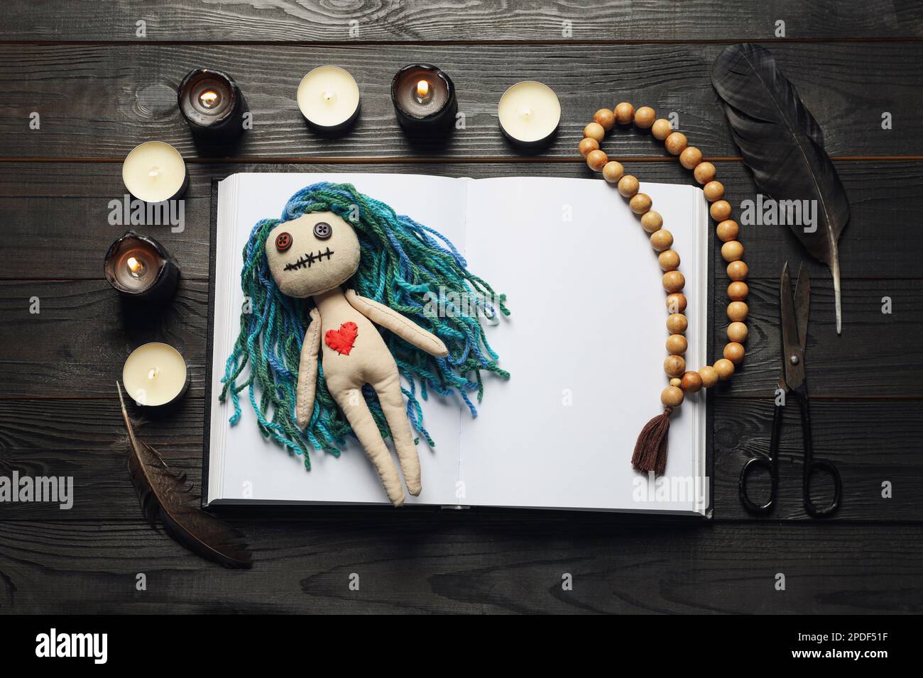 Flache Komposition mit Voodoo-Puppe auf dunklem Holztisch Stockfoto