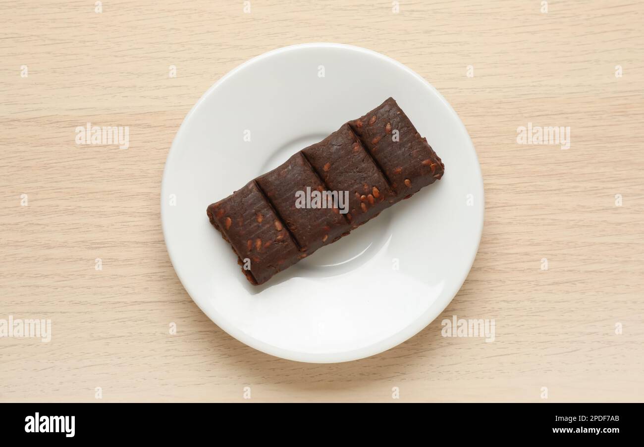 Weißer Teller mit köstlichem und gesundem Hämatogen-Riegel auf Holztisch, Draufsicht Stockfoto