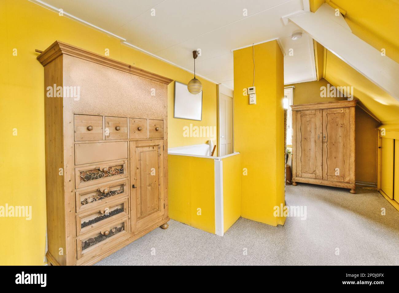 Ein Raum mit gelben Wänden und Holzmöbeln in der Ecke, der auch als Aufbewahrungsraum für Weinflaschen dient Stockfoto