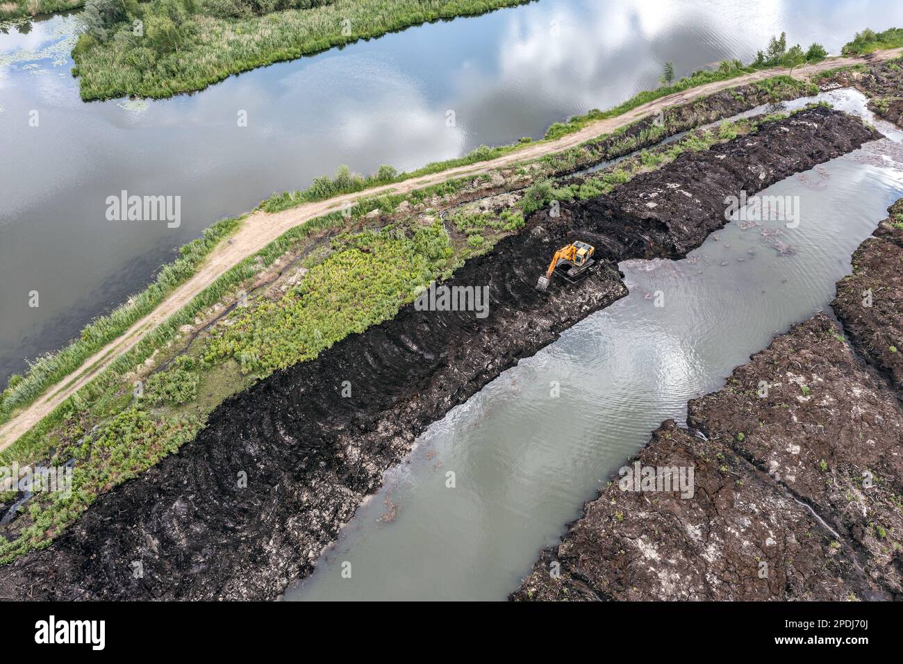 Graben von Entwässerungsgräben im Torfabbau mit Baggern. Luftaufnahme mit Drohne. Stockfoto