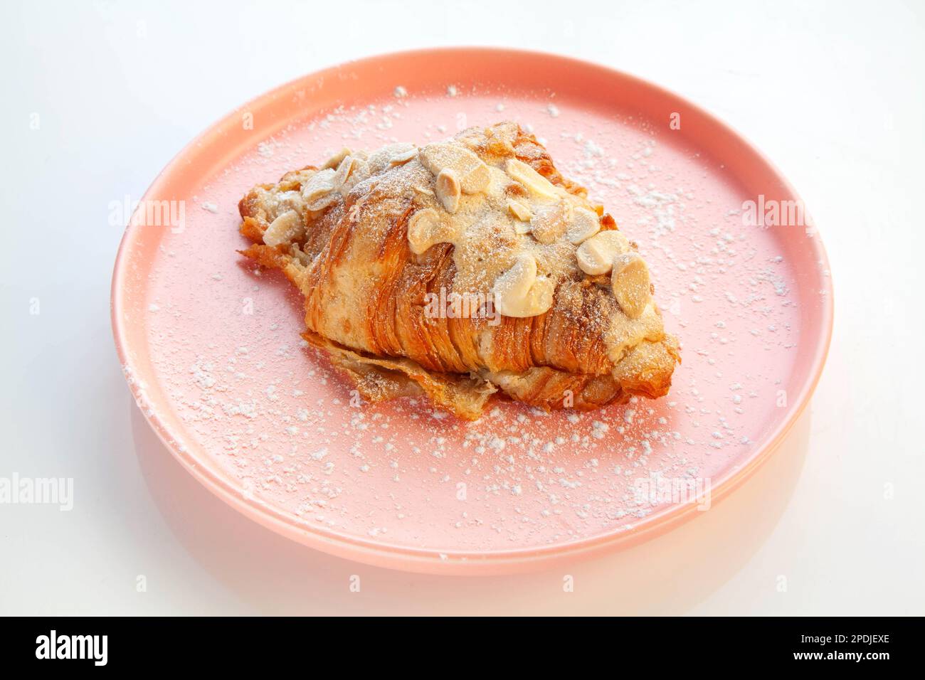 Mandelcroissant auf einem rosa Teller. Stockfoto