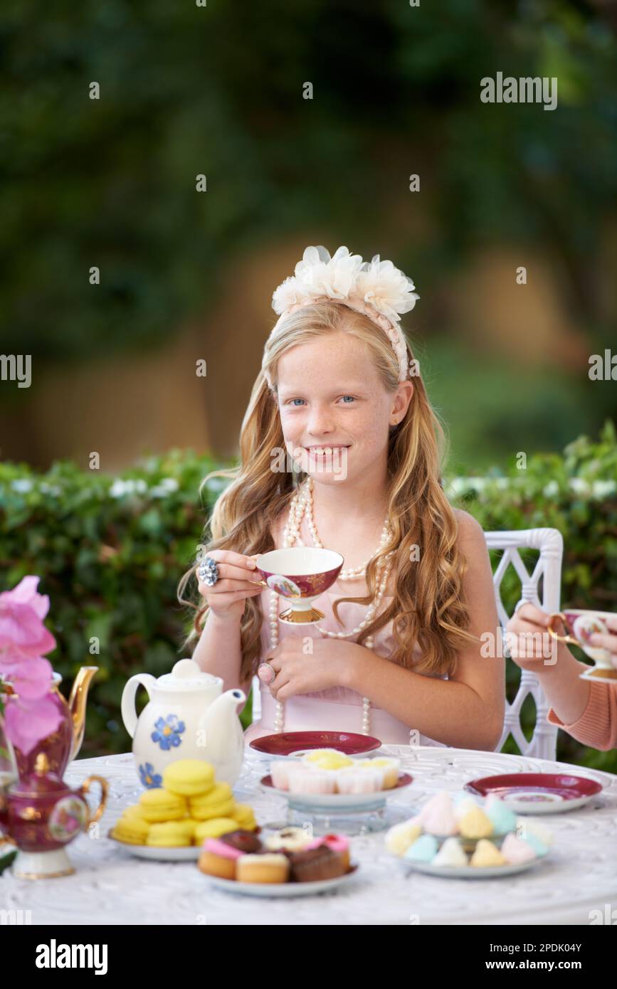 Ein Fantasieflug. Ein süßes kleines Mädchen, das draußen eine Teeparty veranstaltet. Stockfoto