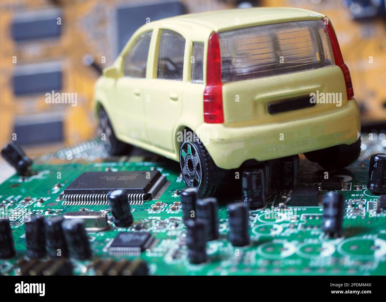 Spielzeugauto auf elektronischer Leiterplatte mit Prozessor. Chip und Halbleiter für die Automobilindustrie. Weltweite Verknappung von Autochips. Stockfoto