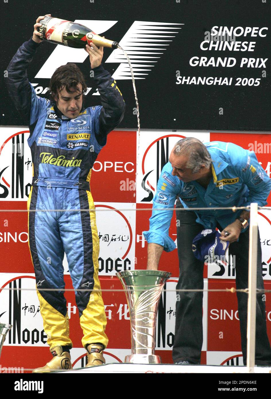Spanish Formula One world champion Fernando Alonso, left, pours champagne to the Formula One constructors championship trophy on the podium as Renault team director Flavio Briatore looks on during the award ceremony after Alonso won the Chinese Formula One Grand Prix at Shanghai International Circuit, China, Sunday, Oct. 16, 2005. (AP Photo/Ng han Guan) Stockfoto