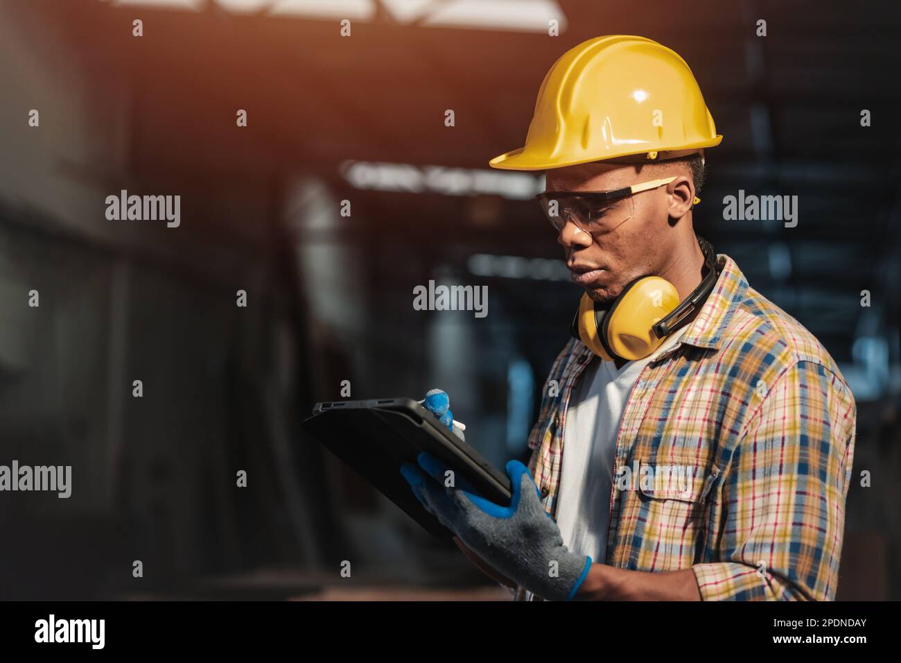 Werkstattarbeiter, der die drahtlose Online-Tablet-Technologie für die computergestützte Konstruktion bei der Arbeit nutzt Stockfoto