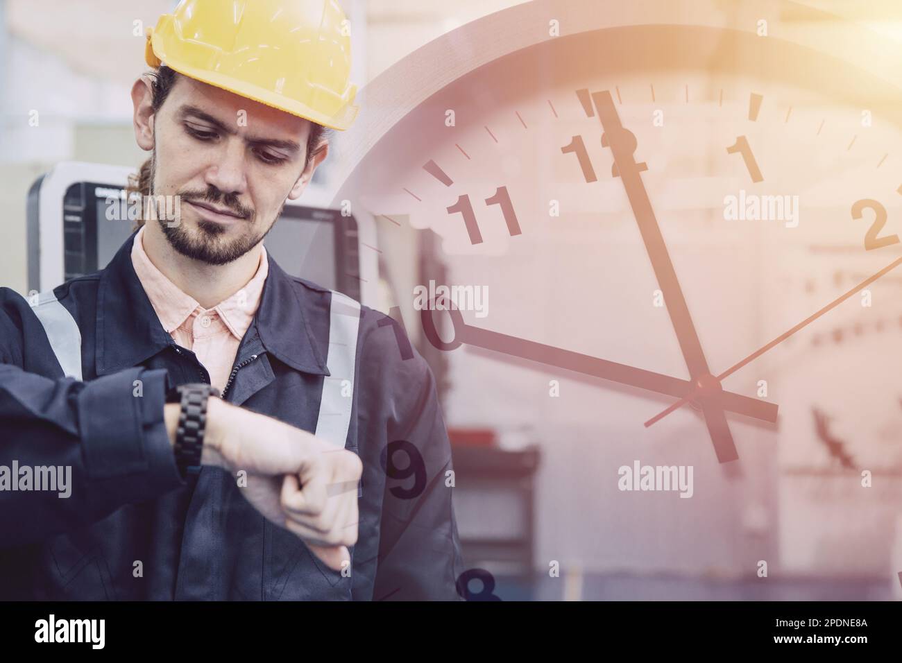 Ingenieurmitarbeiter machen sich Sorgen, wenn sie auf die Armbanduhr schauen, die die Uhr überlagert. Konzept für späte Arbeitszeiten in Industriebetrieben. Stockfoto