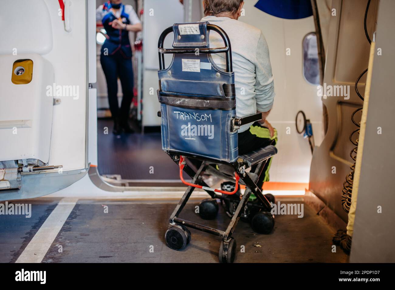Rückansicht eines Mannes auf einem speziellen Rollstuhl für den Transport im Flugzeug. Das Konzept des Reisenden mit besonderen Bedürfnissen. Stockfoto