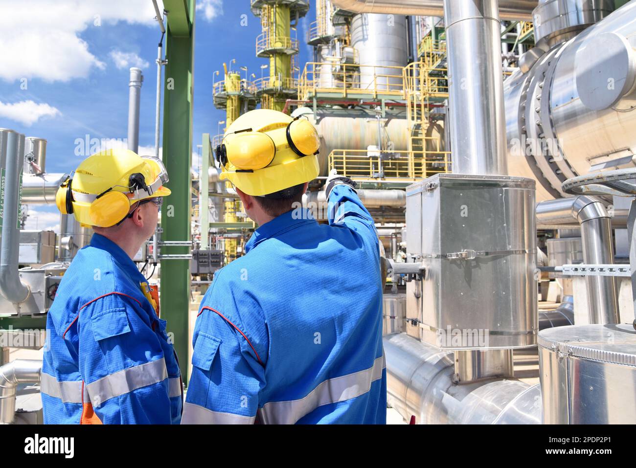 Chemische Industrie Anlage - Arbeiter in Arbeitskleidung in einer Raffinerie mit Rohren und Maschinen Stockfoto