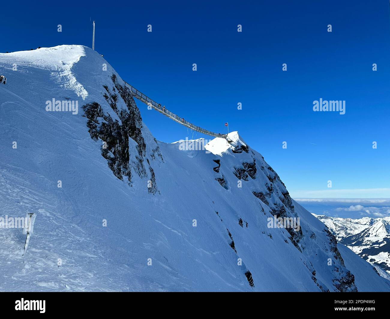 Ein atemberaubender Blick auf eine Hängebrücke zwischen zwei Gipfeln eines weißen schneebedeckten Berges Stockfoto