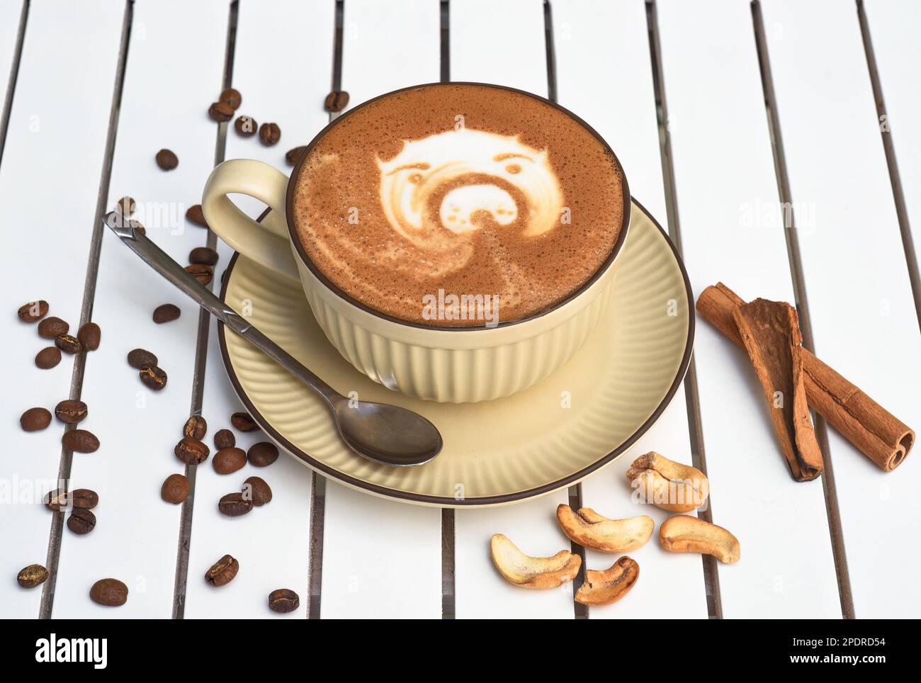 Eine Tasse Nuss-Cappuccino mit Löffel und Zucker auf einem weißen Holztisch mit seitlichem Blick Stockfoto