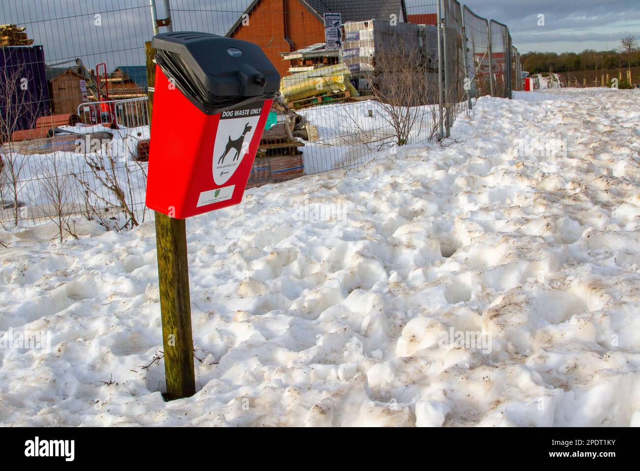 In Framlingham Suffolk hebt sich eine rote Mülltonne für Hundekacke von überraschend tiefem Schnee ab Stockfoto