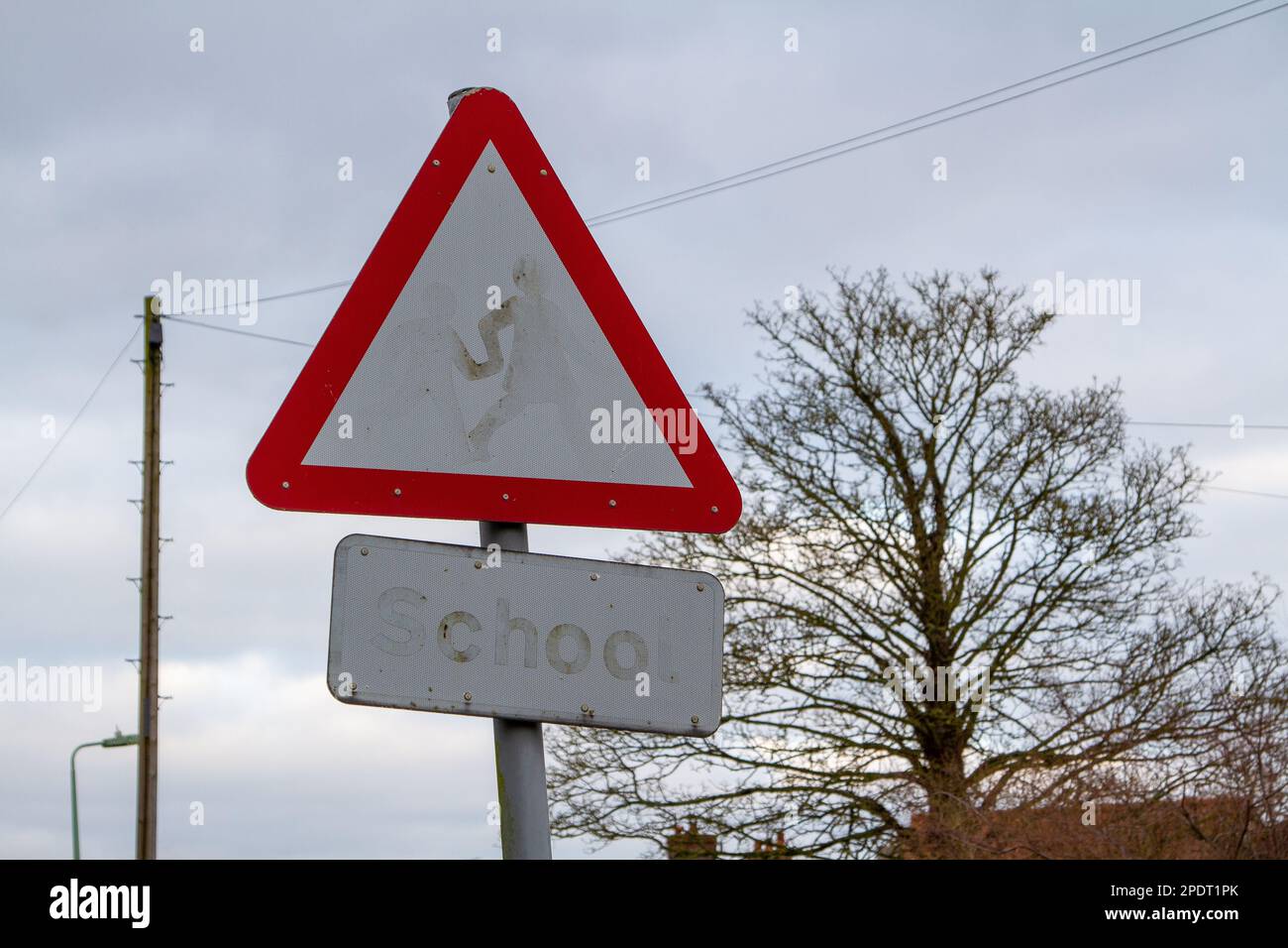 In einer ruhigen Wohnstraße in einer kleinen Marktstadt in Suffolk ist ein Schulwarnschild so verblasst, dass es nutzlos ist Stockfoto