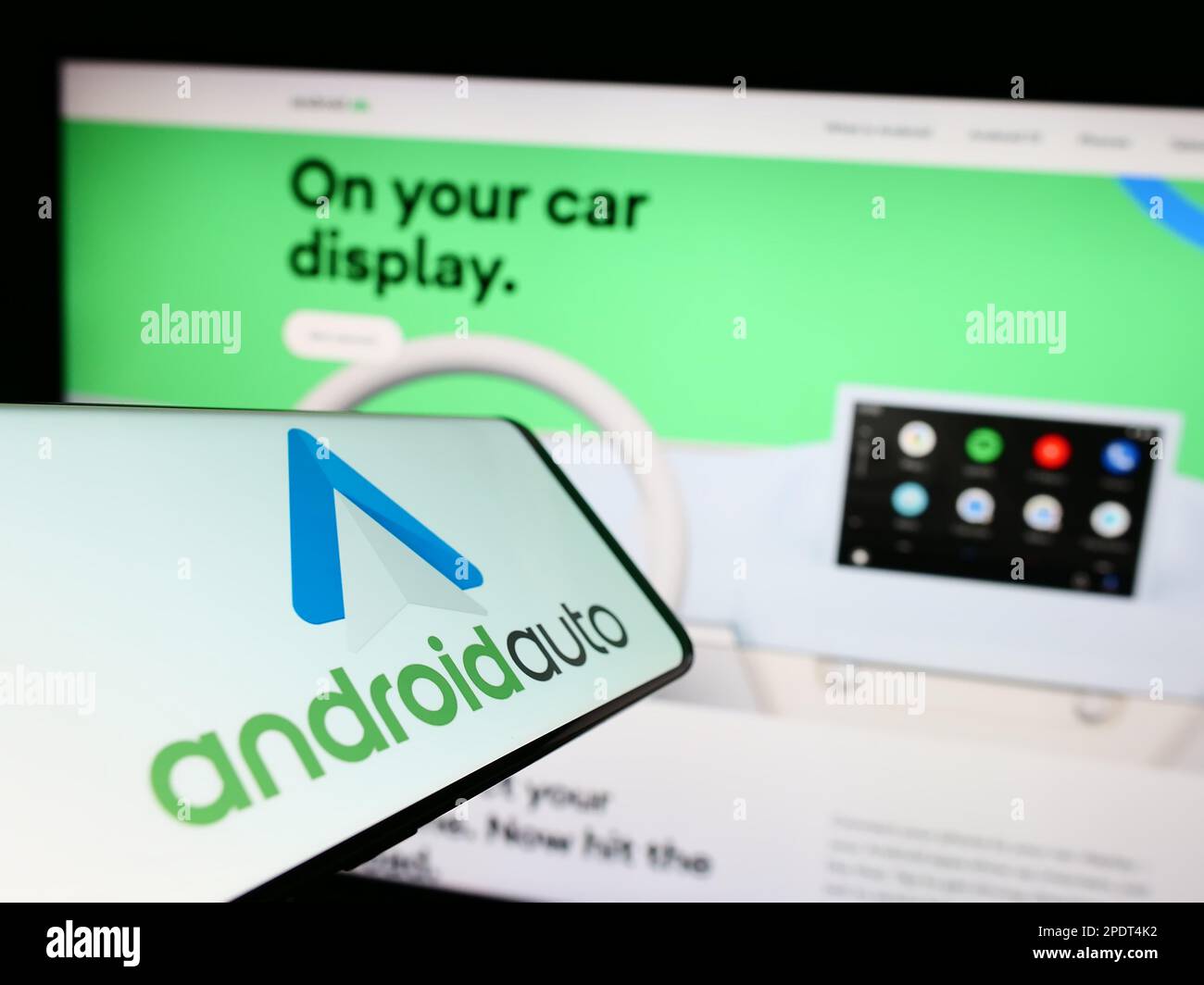 Mobiltelefon mit Logo der mobilen App Android Auto (Google) auf dem Bildschirm vor der Website. Fokus auf die Mitte rechts des Telefondisplays. Stockfoto