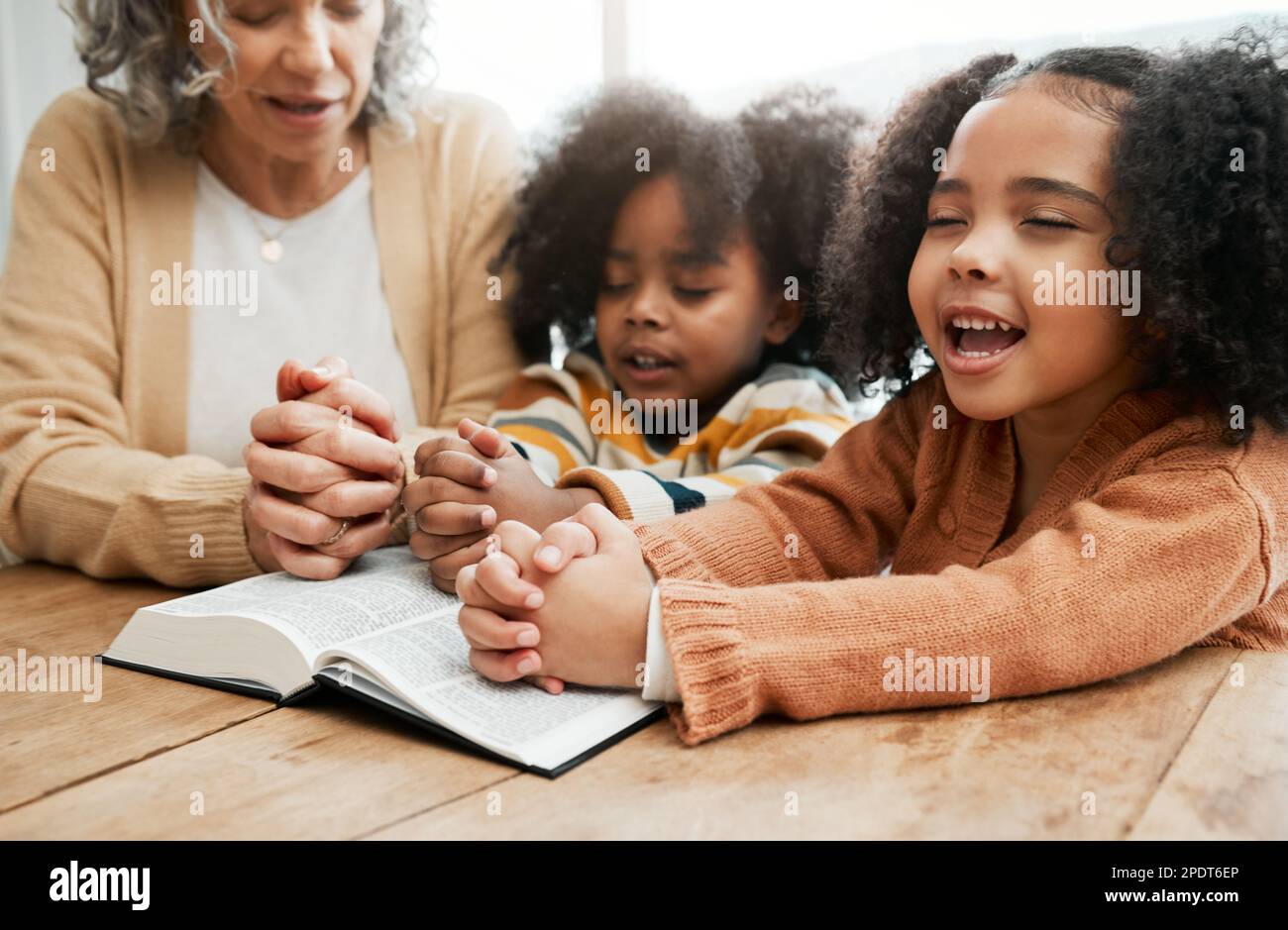 Bibel, Gottesdienst oder Großmutter beten mit Kindern oder Geschwistern um Gebete, Unterstützung oder Hoffnung im Christentum. Kindererziehung, Familie oder alte Frau Stockfoto