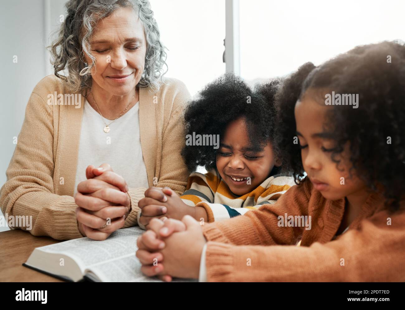 Bibel, Gebet oder Großmutter, die mit Kindern oder Geschwistern um Gottesdienst, Unterstützung oder Hoffnung im Christentum betet. Kindererziehung, Familie oder alte Frau Stockfoto
