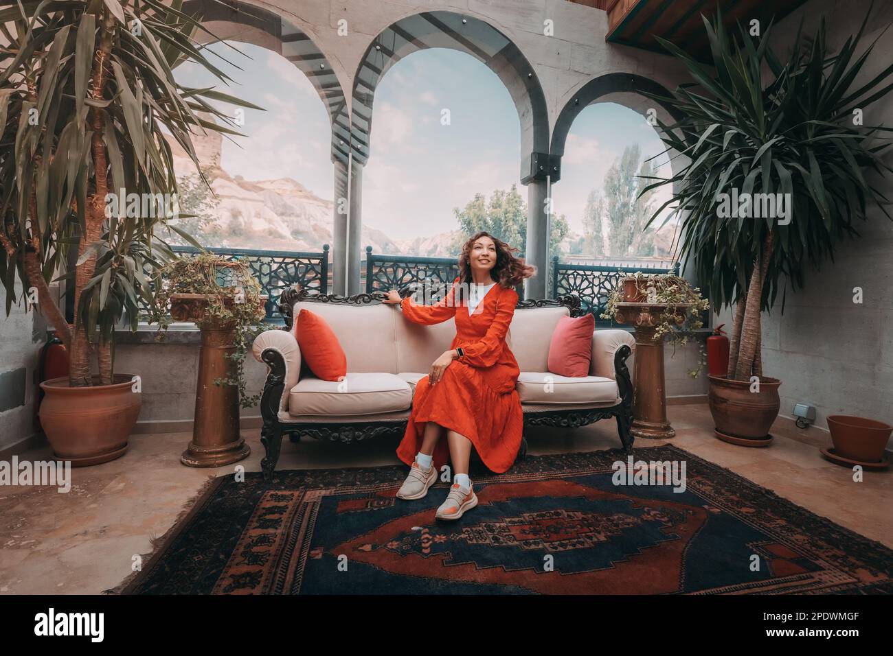 Ein Mädchen sitzt bequem in einem authentischen türkischen Hotel in Kappadokien, umgeben von der einzigartigen und exotischen Architektur der Region. Stockfoto