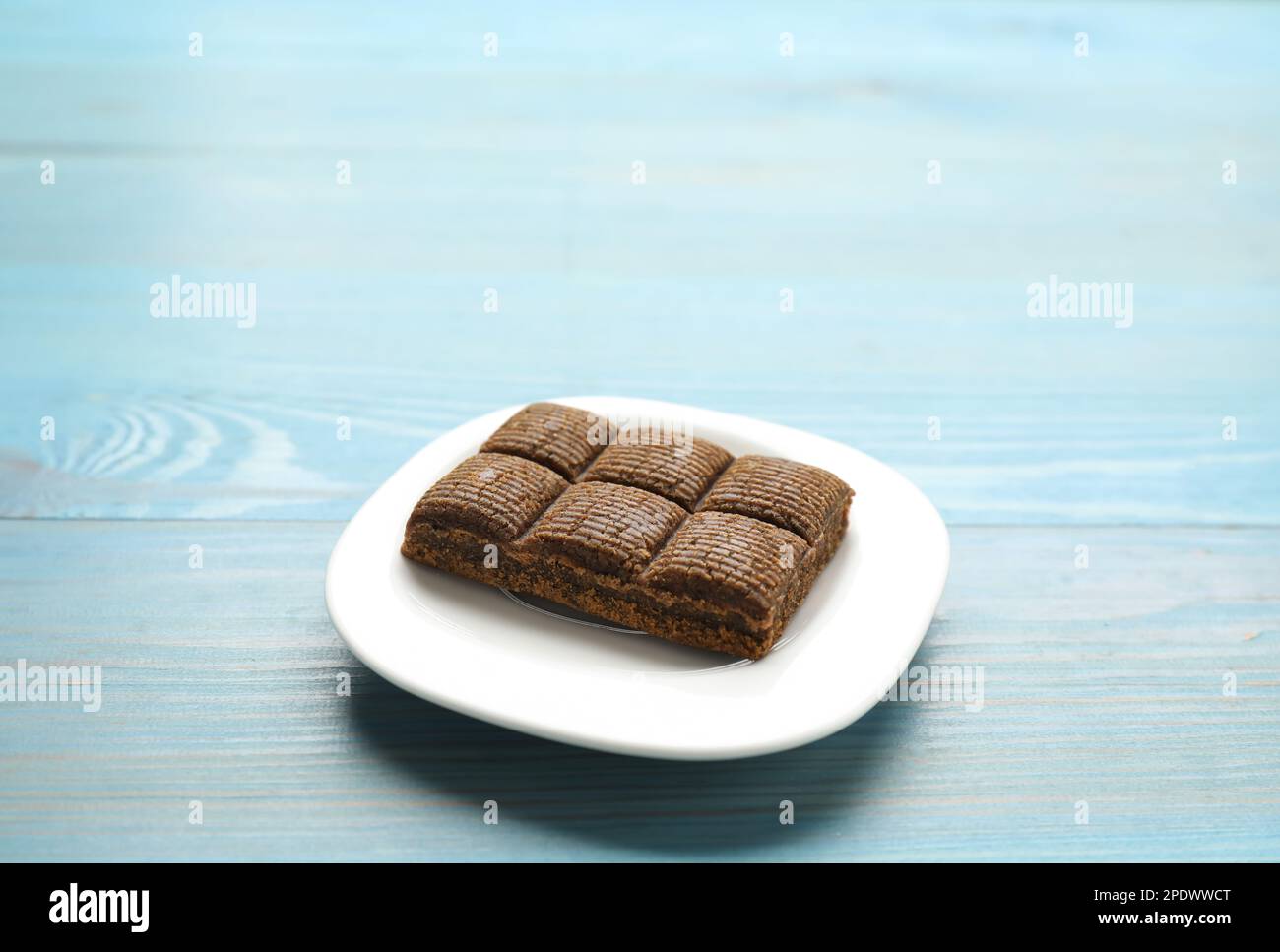 Weißer Teller mit köstlichem und gesundem Hämatogenriegel auf blauem Holztisch. Platz für Text Stockfoto