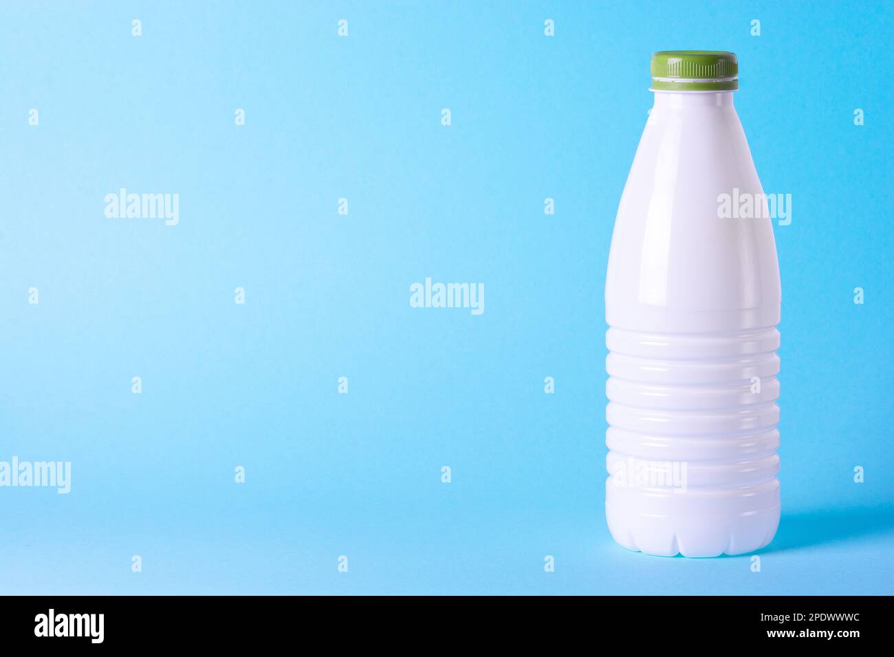 Weiße Kunststoffflasche auf hellblauem Hintergrund mit Grapefruit. Gesunde Ernährung. Milchprodukte. Frisches Obst Stockfoto