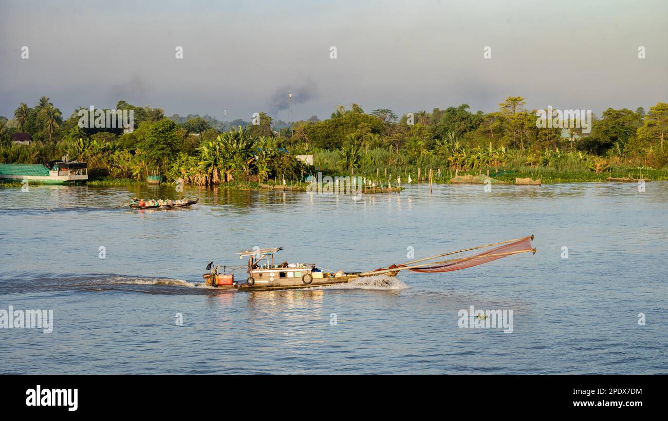 Ein hölzernes Fischerboot mit Mann und Frau fährt auf dem Mekong in der Nähe von Long Xuyen in Vietnam. Stockfoto