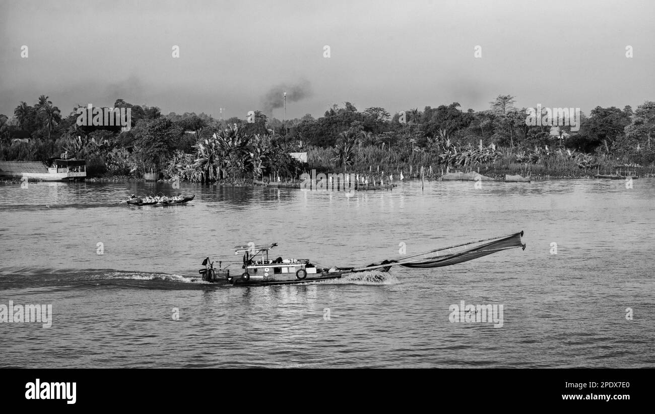 Ein hölzernes Fischerboot mit Mann und Frau fährt auf dem Mekong in der Nähe von Long Xuyen in Vietnam. Stockfoto