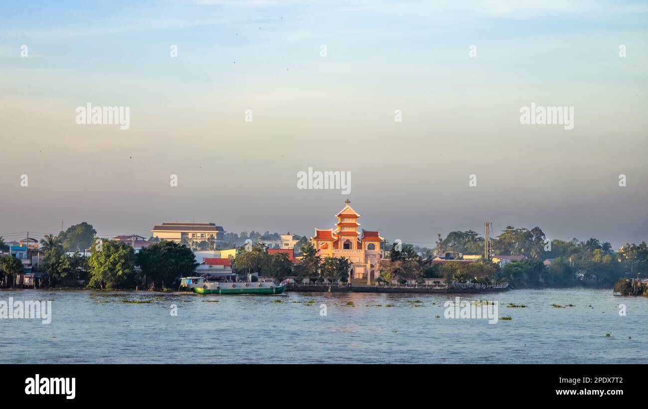 Eine Kirche im östlichen Stil und andere Gebäude am Ufer des Mekong bei Long Xuyen im Mekong Delta in Vietnam. Stockfoto