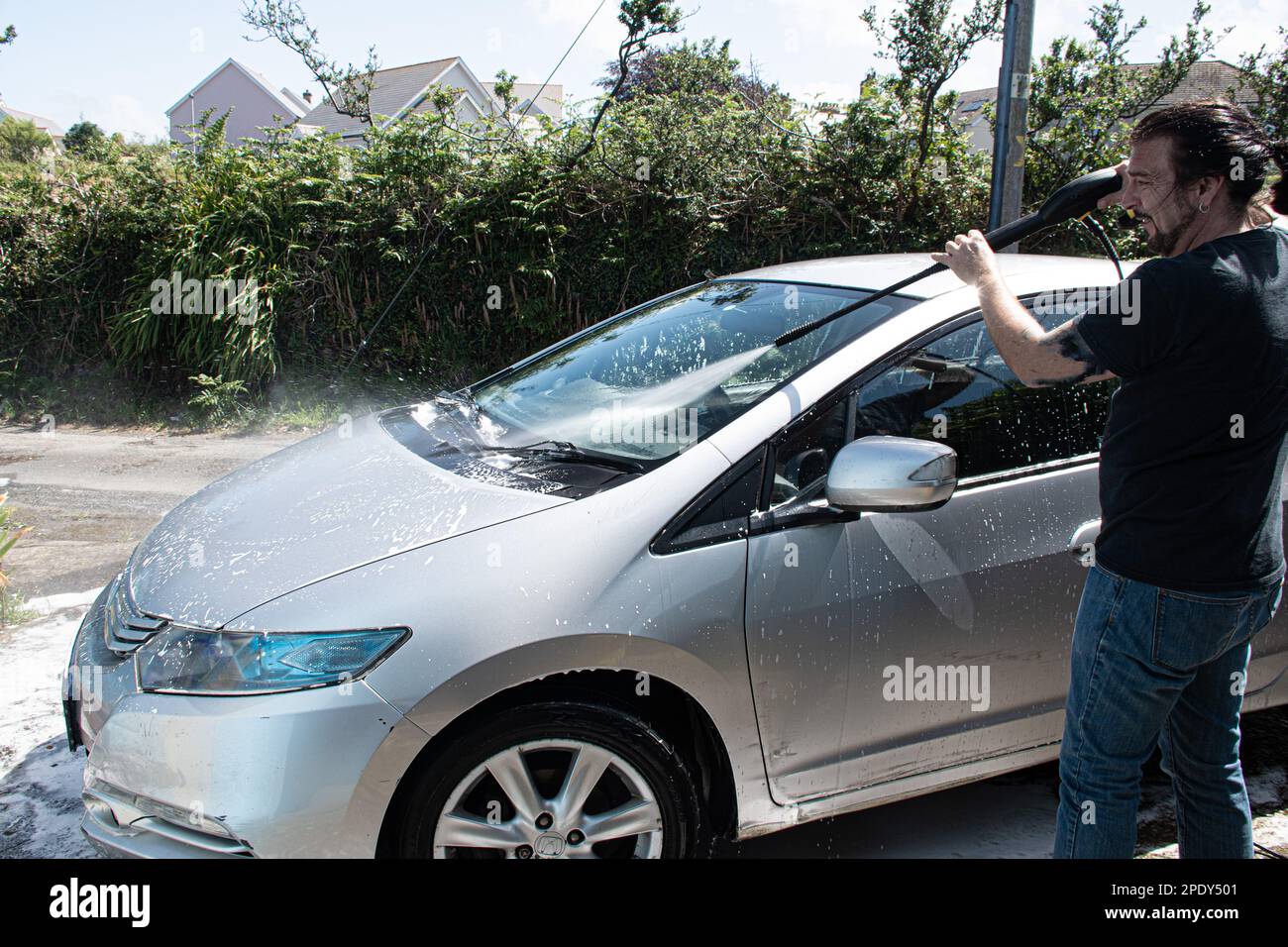 Zwei Masern reinigen einen silbernen Auto-Sprühschaum mit einem Hochdruckreiniger ein Auto waschen Stockfoto