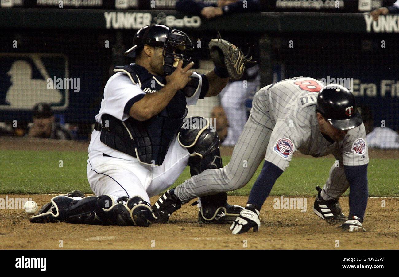 Minnesota Twins' Nick Punto, pinch running for Twins Michael Cuddyer, scores the tying run as Seattle Mariners catcher Wiki Gonzalez can't hang onto the throw in the ninth inning Wednesday, Aug. 10, 2005, at Safeco Field in Seattle. (AP Photo/Ted S. Warren) Stockfoto