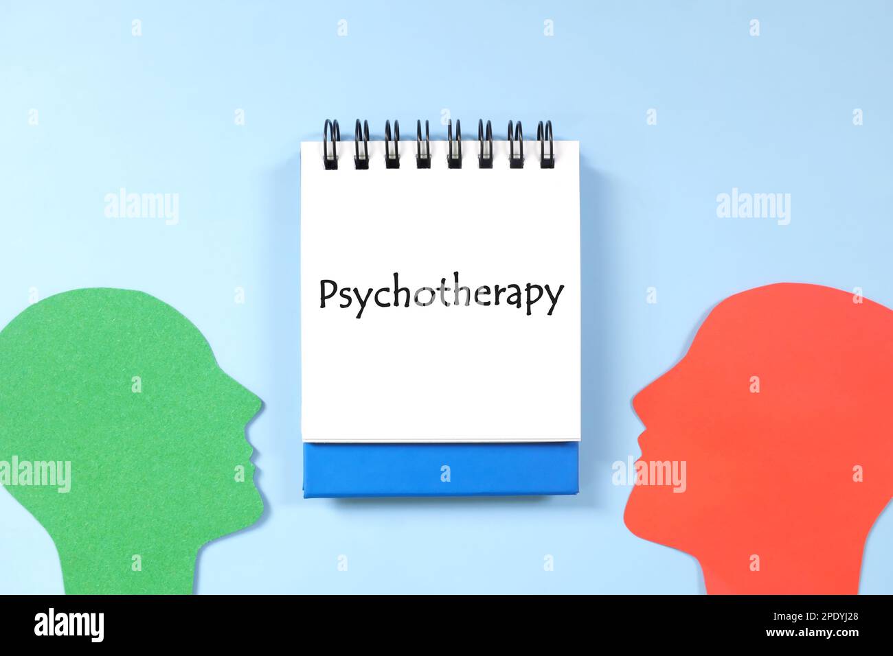 Psychotherapie im psychischen Gesundheitskonzept. Flache Laienzusammensetzung des menschlichen Kopfprofils von Angesicht zu Angesicht mit blauem Notizblock. Stockfoto