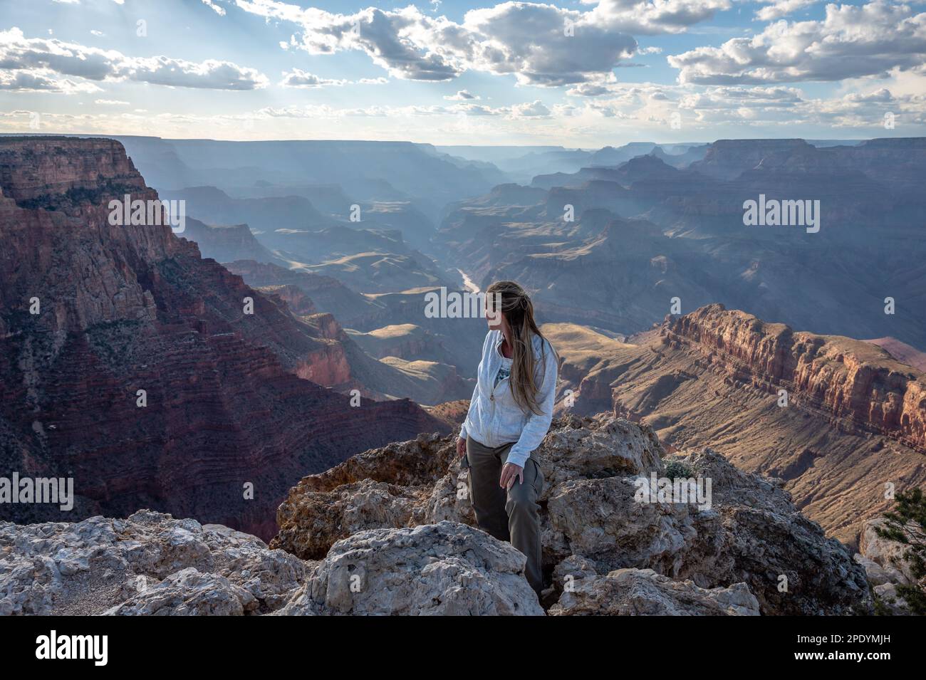 Ein junges blondes Mädchen steht am Rand des Abgrunds des Grand Canyon und blickt auf die Landschaft Stockfoto