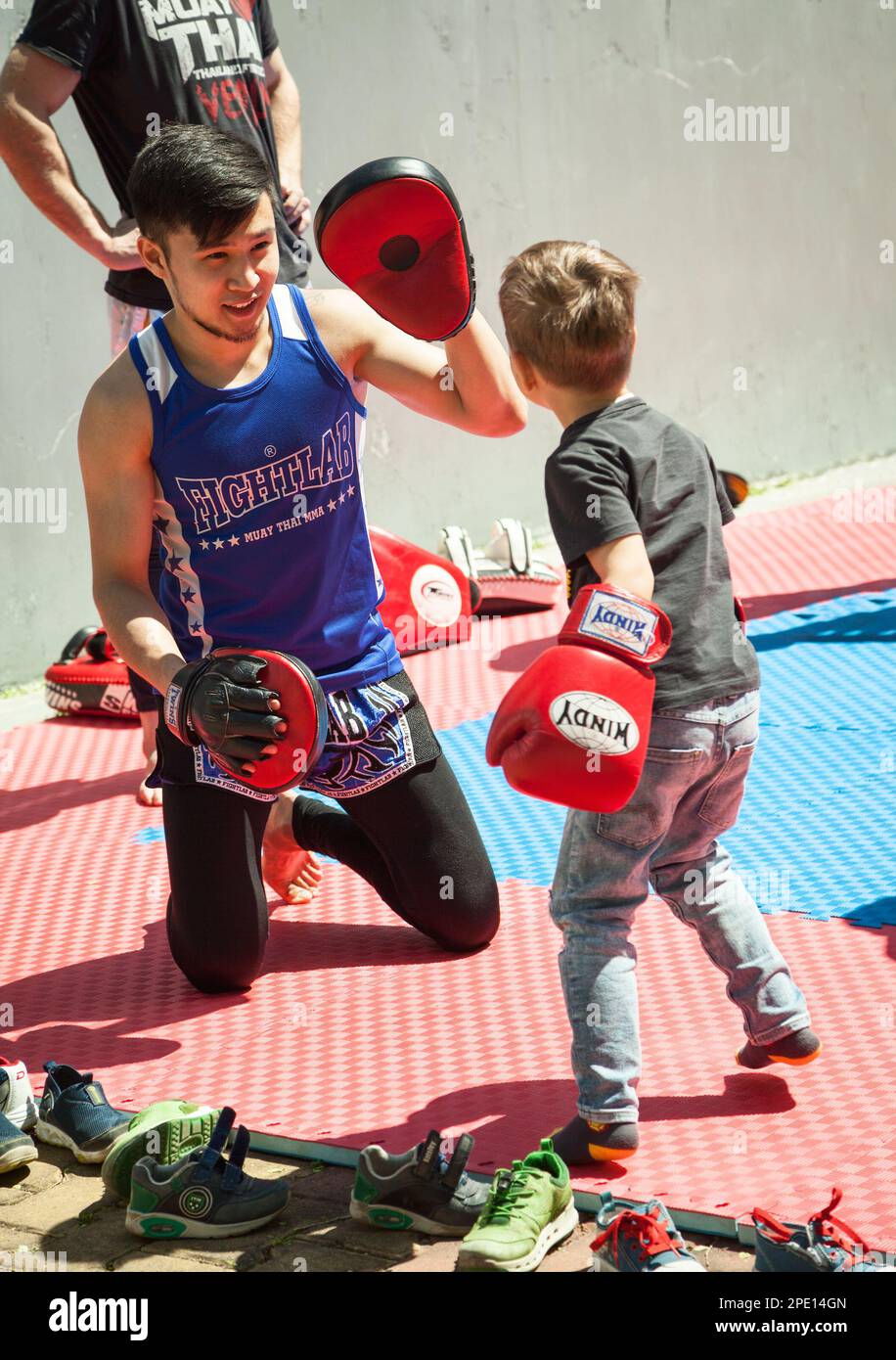 Khabarowsk, Russland - 20. Mai 2017: Junger asiatischer Boxer trainiert ein kleines Kind in Muay Thai. Ein kleiner Junge in Boxhandschuhen, der mit einem Trainer im Fitnessstudio trainiert Stockfoto